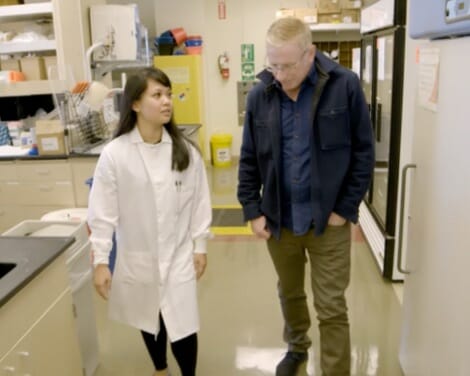 Man and scientist walking across a laboratory and talking