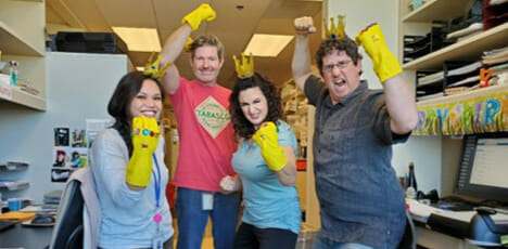 Coworkers wearing brightly decorated yellow gloves on one hand